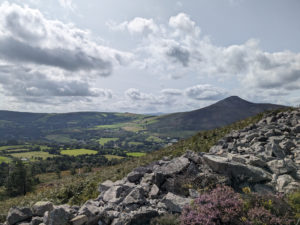 View of the Big Sugarloaf from the Little Sugar Loaf. The sky is cloudy and the mountains look rugged and still green.